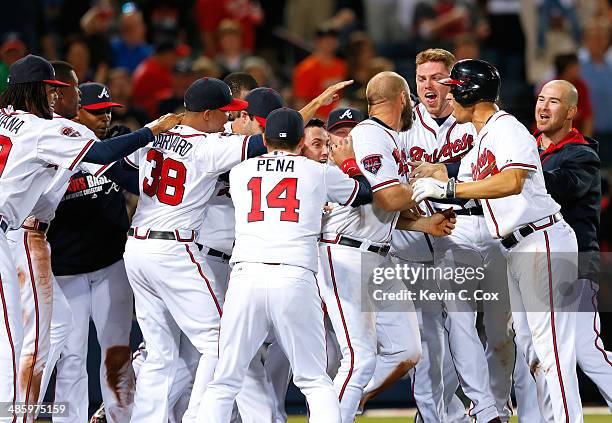 Evan Gattis of the Atlanta Braves celebrates with his teammates after hitting a walk-off homer in the tenth inning that scored Dan Uggla in their 4-2...