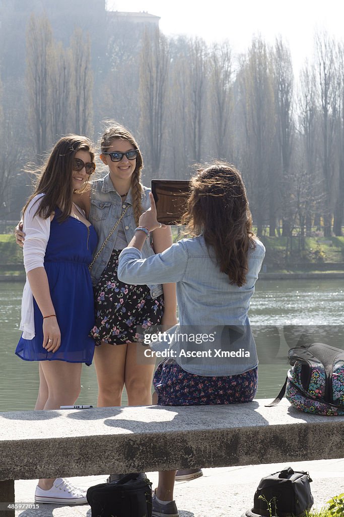 Teens take pic with digital tablet, at river's erg