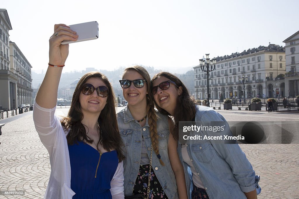 Teen girls take selfie pic in urban piazza