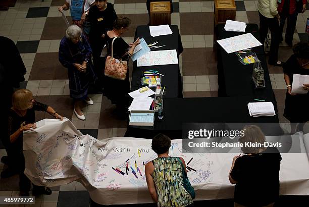 Community members sign a large roll of paper with words and prayers for the families of Alison Parker and Adam Ward following the Interfaith Service...