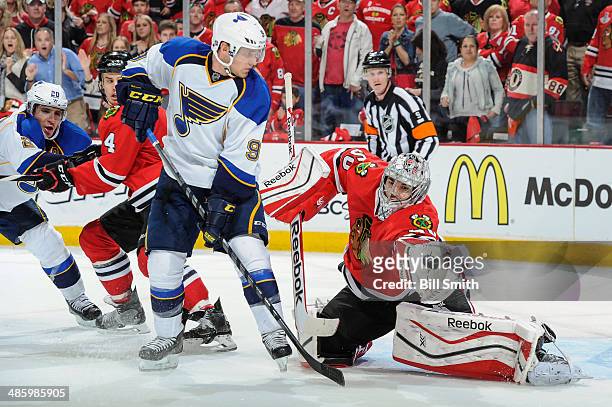 Goalie Corey Crawford of the Chicago Blackhawks grabs the puck next to Jaden Schwartz of the St. Louis Blues, as Alexander Steen of the Blues and...