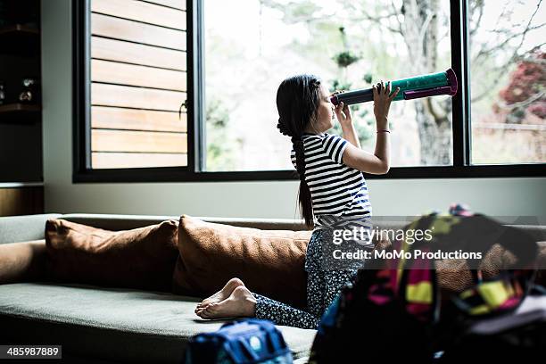 girl looking out window with telescope - child discovering science stock pictures, royalty-free photos & images