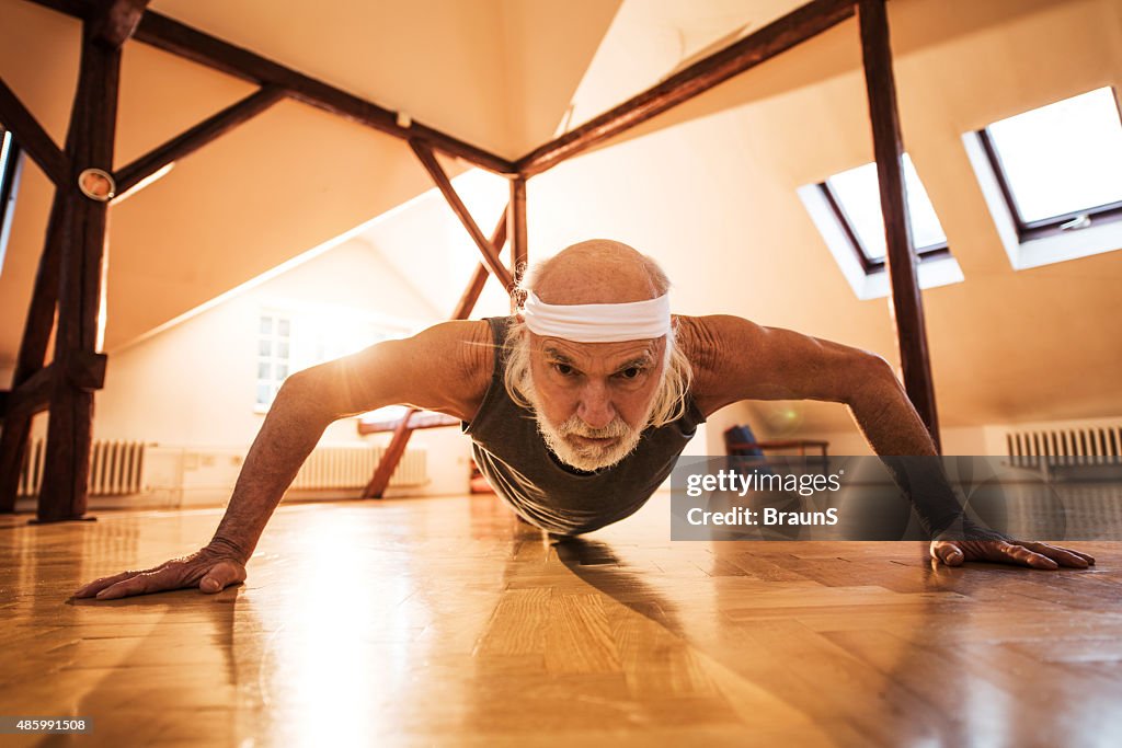 Elderly man exercising push-ups in a health club.