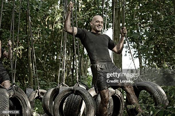 man having fun during tyre obstacle in forest - mud run stock pictures, royalty-free photos & images