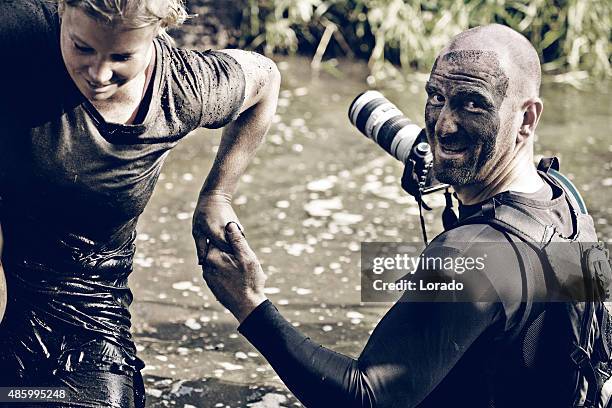 male photographer helping woman during mud run obstacle - mud stock pictures, royalty-free photos & images