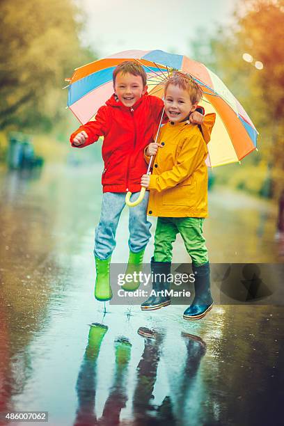 niños en lluvia - charco fotografías e imágenes de stock
