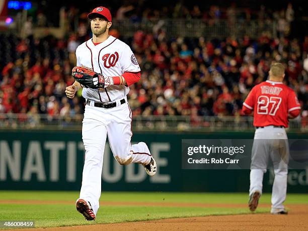 Bryce Harper of the Washington Nationals jogs past Mike Trout of the Los Angeles Angels after Trout lined out for the third out of the seventh inning...