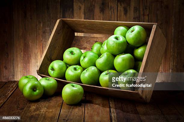 green apples in a crate on rustic wood table - green apples stock pictures, royalty-free photos & images