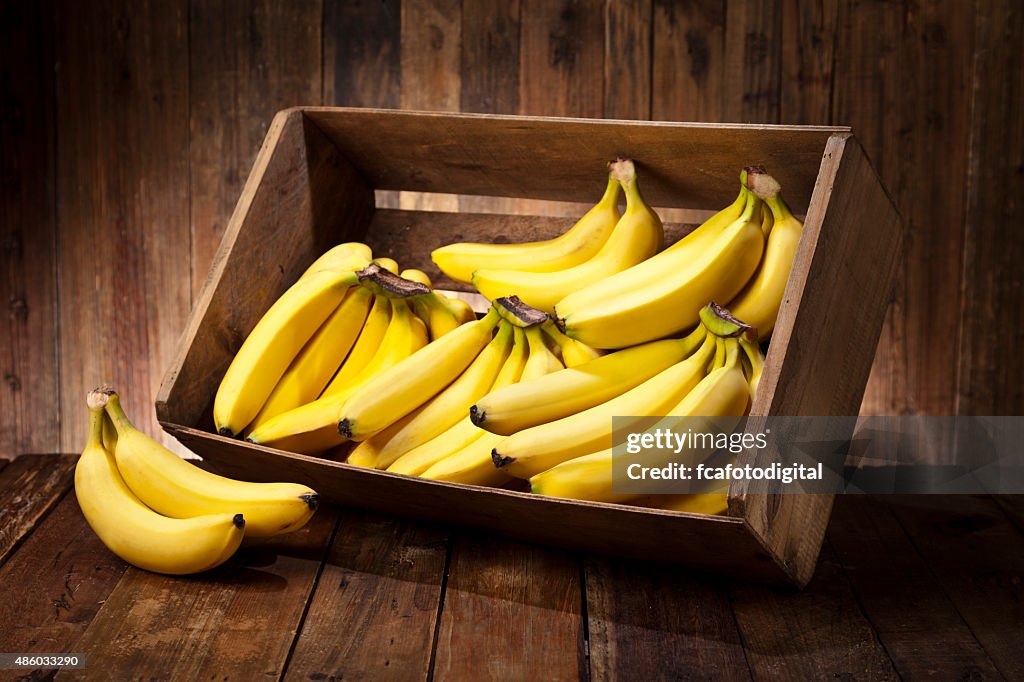 Bananas in a crate on rustic wood table