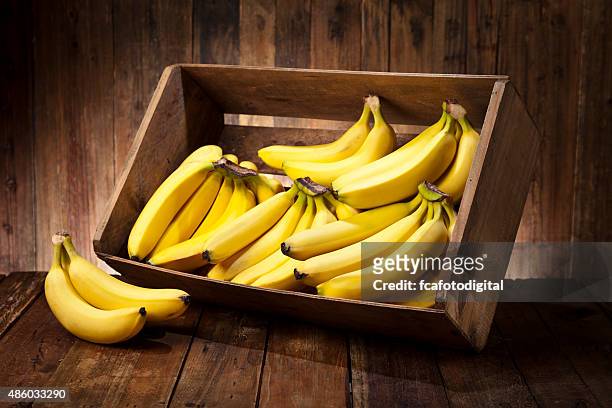 bananas in a crate on rustic wood table - fruit box stock pictures, royalty-free photos & images
