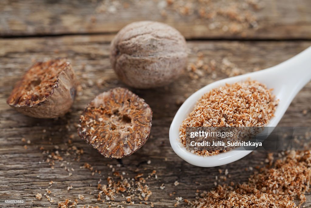 Nutmeg whole and grated on wooden background