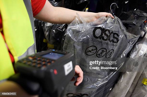 Worker uses a wrist-mounted device to scan an item of clothing ahead of shipping at Asos Plc's distribution warehouse in Barnsley, U.K., on Tuesday,...