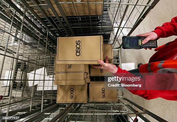 Worker uses a handheld device to scan a box of Asos Plc own-brand shoes at the company's distribution warehouse in Barnsley, U.K., on Tuesday, April...