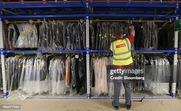 Norbert Dentressangle SA logo sits on a worker's Hi-Vis safety jacket as he re-stocks a clothing rack inside Asos Plc's distribution warehouse in...