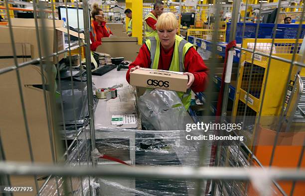 Worker places a completed customer order into a trolley at Asos Plc's distribution warehouse in Barnsley, U.K., on Tuesday, April 22, 2014. Asos, the...