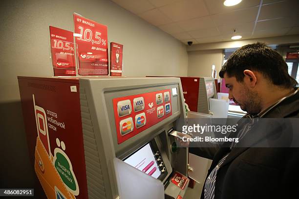 Logos for Russian and U.S. Card payment systems, including Visa Inc. And Mastercard Inc., sit on an automated teller machine used by a customer...