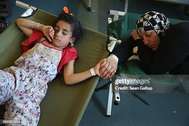 Mother and daughter clutch hands as they sleep on cots at a registration center for migrants at a facility of the German Federal Police on August 31,...