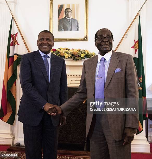 Zimbabwe's President Robert Mugabe shakes hands with Africa's richest man, Nigeria's Aliko Dangote prior to their meeting at State House in Harare,...