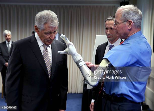 Secretary of Defense Chuck Hagel looks at Vietnam veteran Fred Downs' modular prototype prosthetic arm at the Pentagon on April 22, 2014 in...