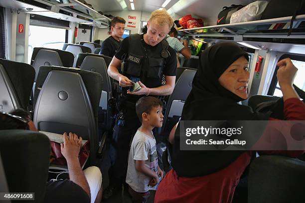 German policeman checks the identity papers of passengers on a train that arrived from Budapest at Rosenheim railway station on August 31, 2015 in...