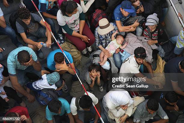 Some of approximately 190 migrants who arrived on a train from Budapest and were detained by German police at Rosenheim railway station wait to be...