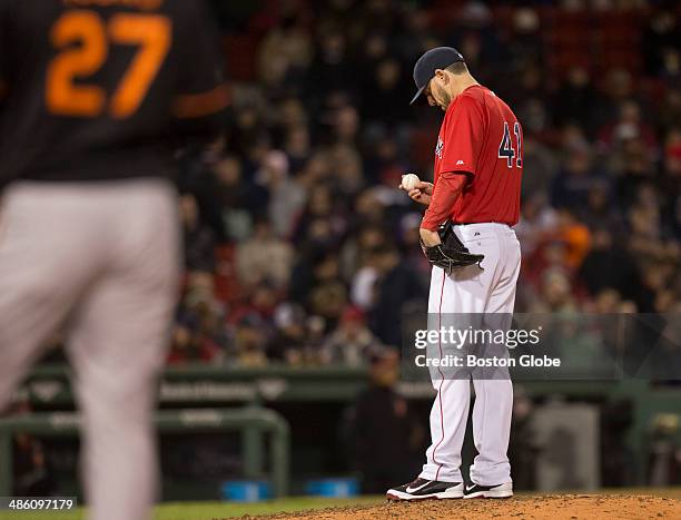Boston Red Sox starting pitcher John Lackey looks down at the ball after giving up a walk to Baltimore Orioles player Delmon Young as manager John...