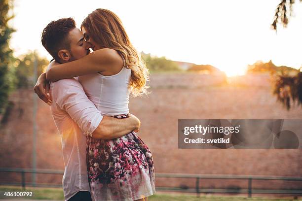 ヤングカップル歩行をお楽しみいただけます。 - young couple kiss ストックフォトと画像