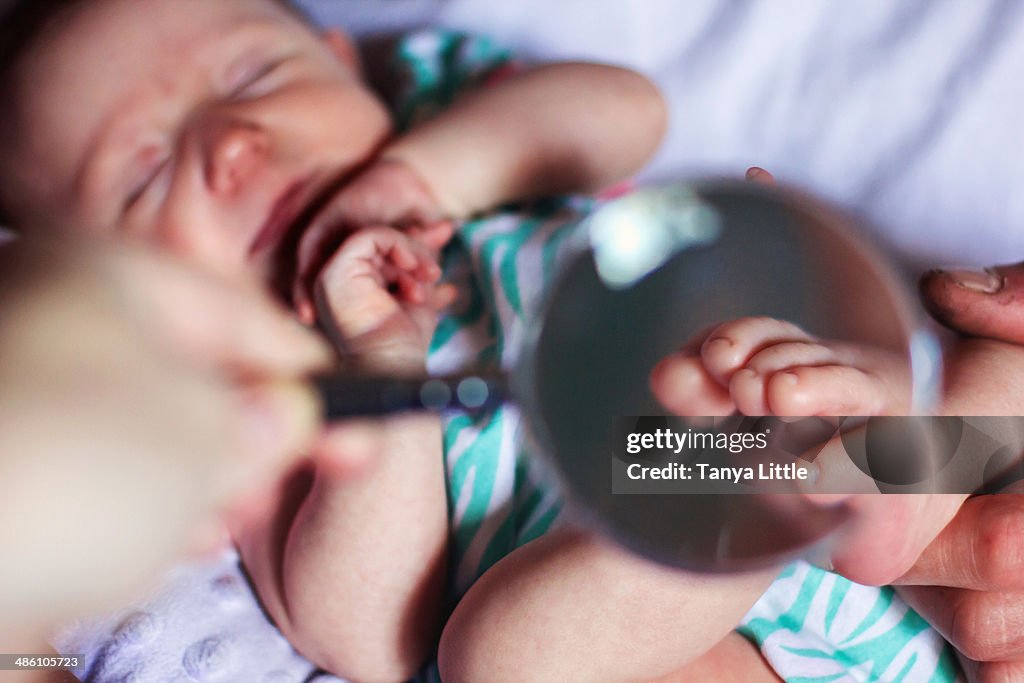 Magnifying glass held over a baby girl's toes