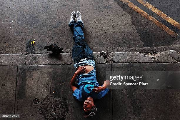 Passed out man lies on a sidewalk in an area which has witnessed an explosion in the use of K2 or 'Spice', a synthetic marijuana drug in East Harlem...