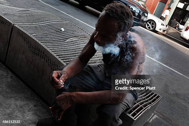 Man smokes K2 or 'Spice', a synthetic marijuana drug, in an area which has witnessed an explosion in the use of K2 in East Harlem on August 31, 2015...