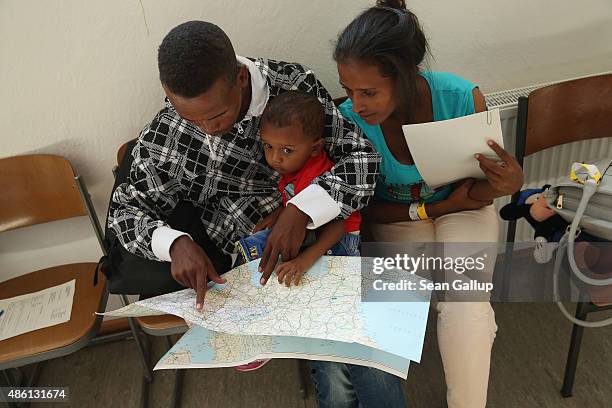 Young migrant couple from Eritrea look on a map of Europe as they prepare to depart with their son after they completed the registration process at a...