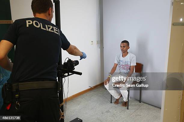 German policeman prepares to photograph a newly-arrived migrant from Eritrea as part of the registration process at a center for migrants at a...