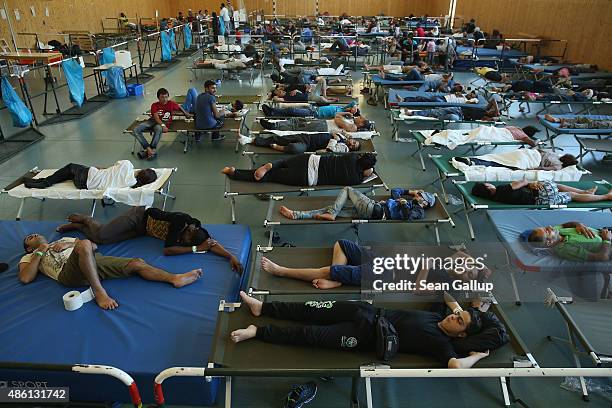 Migrants who had arrived by train to Germany sleep on cots while waiting to register at a center for migrants at a facility of the German Federal...