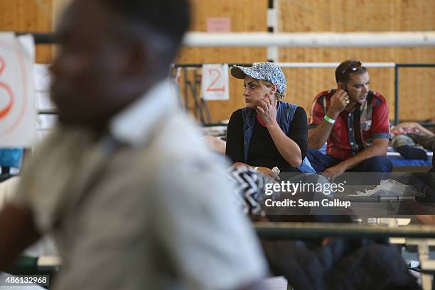 Migrants who had arrived by train to Germany sit on cots while waiting to register at a center for migrants at a facility of the German Federal...