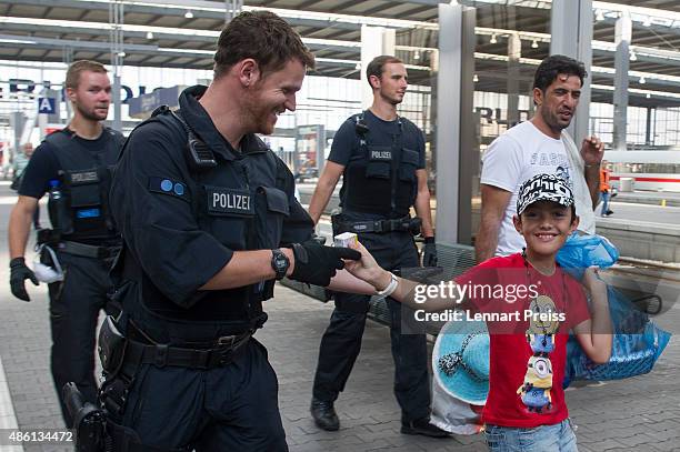 Migrant boy hands over a pack of glucose to a policeman as police detain migrants who arrived at Munich Hauptbahnhof main railway station without...
