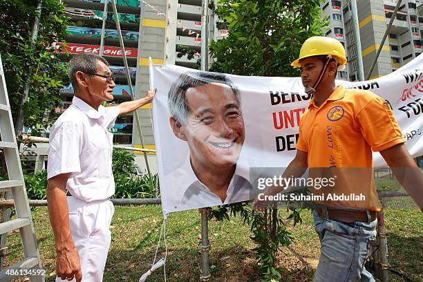 Workers prepare to put up a People's Action Party banner along the roadside after the nomination proceedings have been closed on September 1, 2015 in...