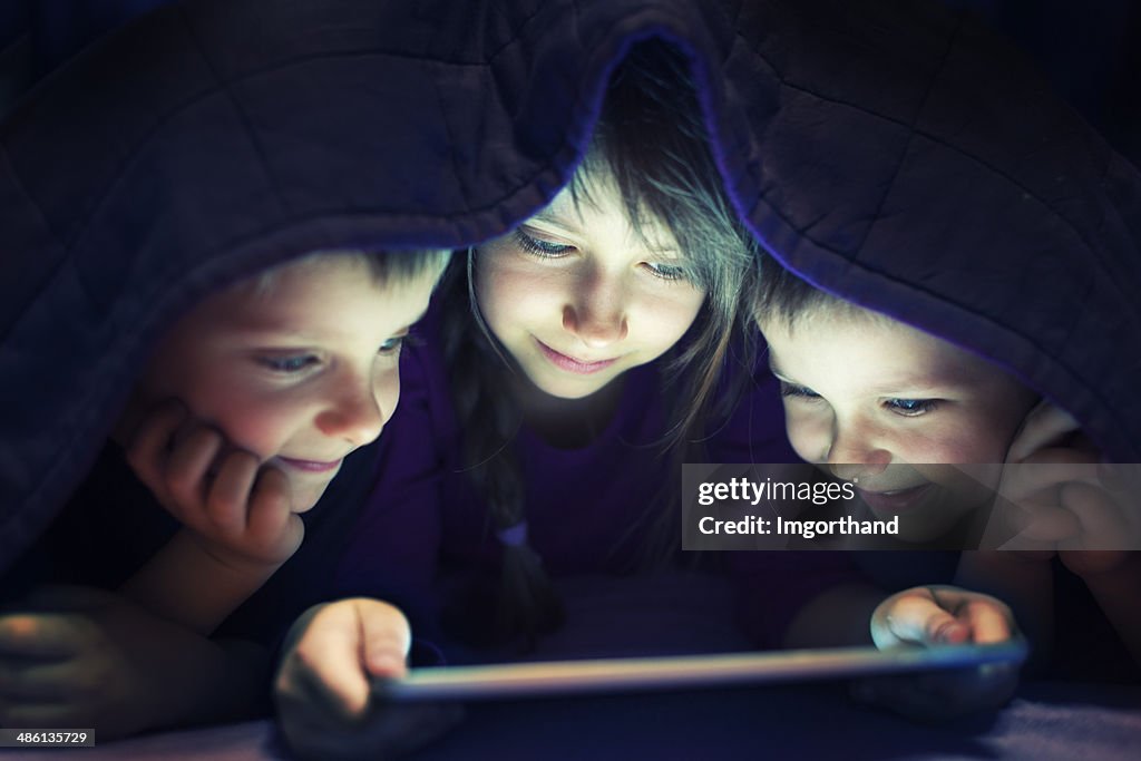 Kids secretly reading book on digital tablet