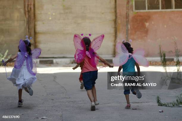 Palestinian girls wearing costumes play in the besieged Yarmuk refugee camp in the Syrian capital Damascus on August 31, 2015. Several thousand...