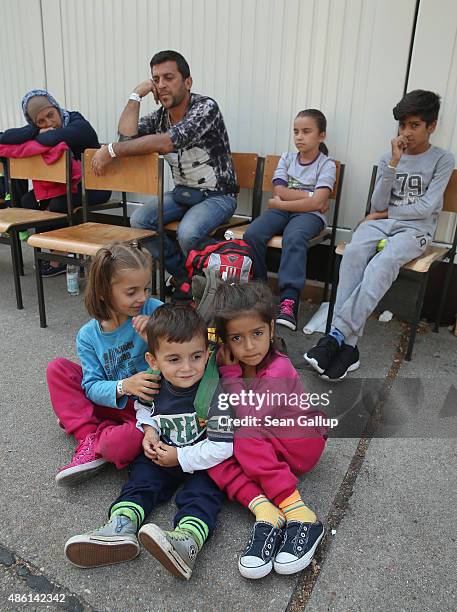 Family of migrants from Syria wait to be taken to a migrants' shelter after they completed the registration process at a facility of the German...