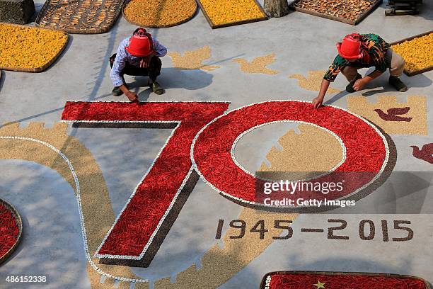 Villagers use dried red chilli peppers, white kidney beans, rice, buckwheat and adzuki beans to create a pattern to celebrate the 70th anniversary of...