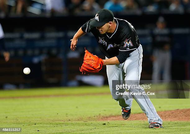 Jose Fernandez of the Miami Marlins scoops up a ground ball by Ryan Doumit of the Atlanta Braves prior to tagging him out down the first base line in...