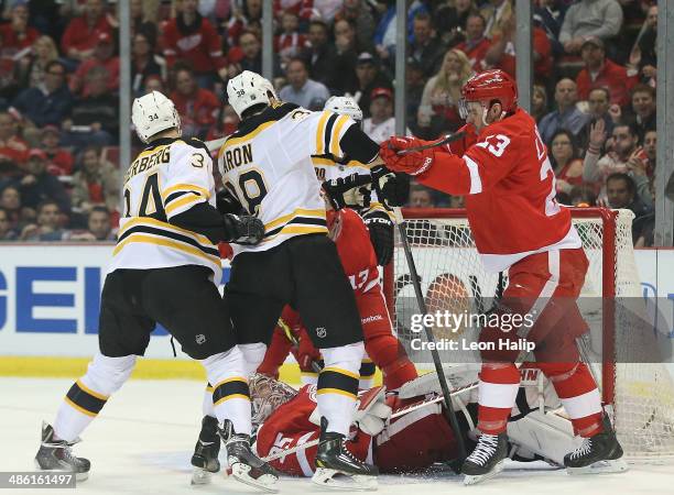 Carl Soderberg and Jordan Caron of the Boston Bruins drive the puck to the net as Jimmy Howard and Brian Lashoff of the Detroit Red Wings defend...