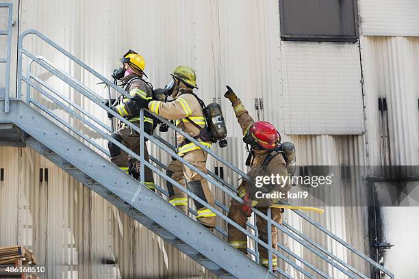 firefighters climbing stairs outside industrial building - brand name stockfoto's en -beelden