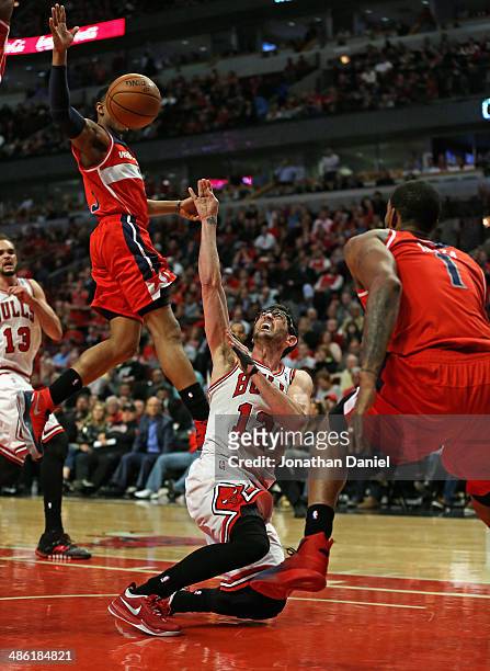 Kirk Hinrich of the Chicago Bulls tries to get off a shot as he hits the floor between Bradley Beal and Trevor Ariza of the Washington Wizards in...