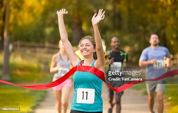 young adult female crossing the finish line - sporthesje stockfoto's en -beelden