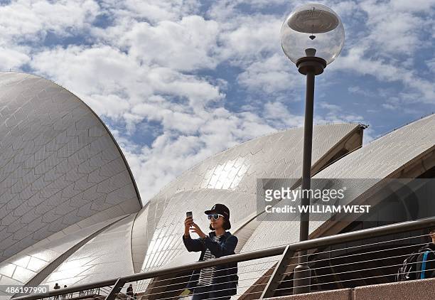 Tourist takes a 'selfie' in front of the Sydney Opera House on September 2 as data showed a boom in cashed-up visitors from China and India has...