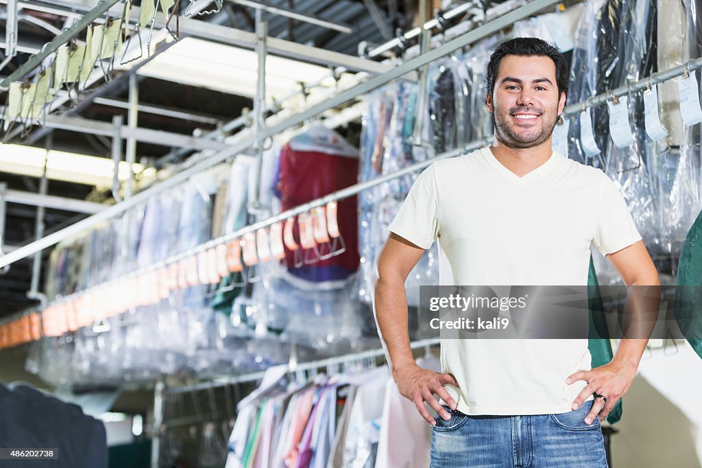 Confident Hispanic man working in dry cleaning store