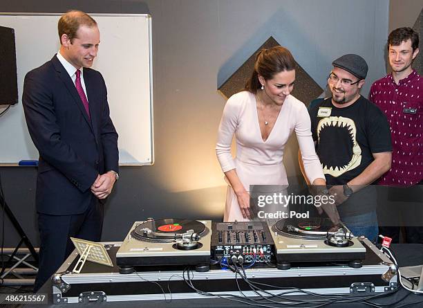 Prince William, Duke of Cambridge looks on as Catherine, Duchess of Cambridge is shown how to play on DJ decks at the youth community centre, The...