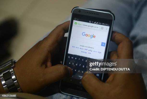 An Indian man surfs on his mobile phone using the Google search engine with its new logo, in Siliguri on September 2,2015. Google refreshed its logo...