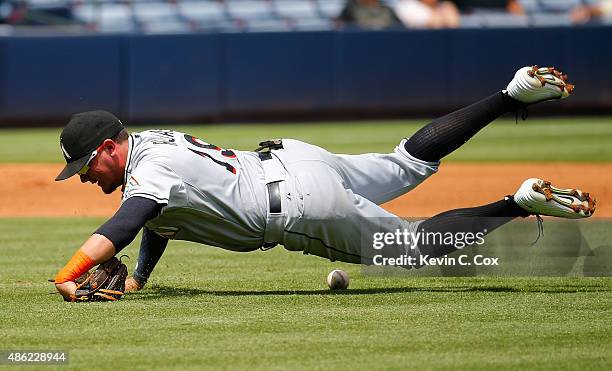 Miguel Rojas of the Miami Marlins falls to the ground as he fails to scoop up a single by Cameron Maybin of the Atlanta Braves in the third inning at...